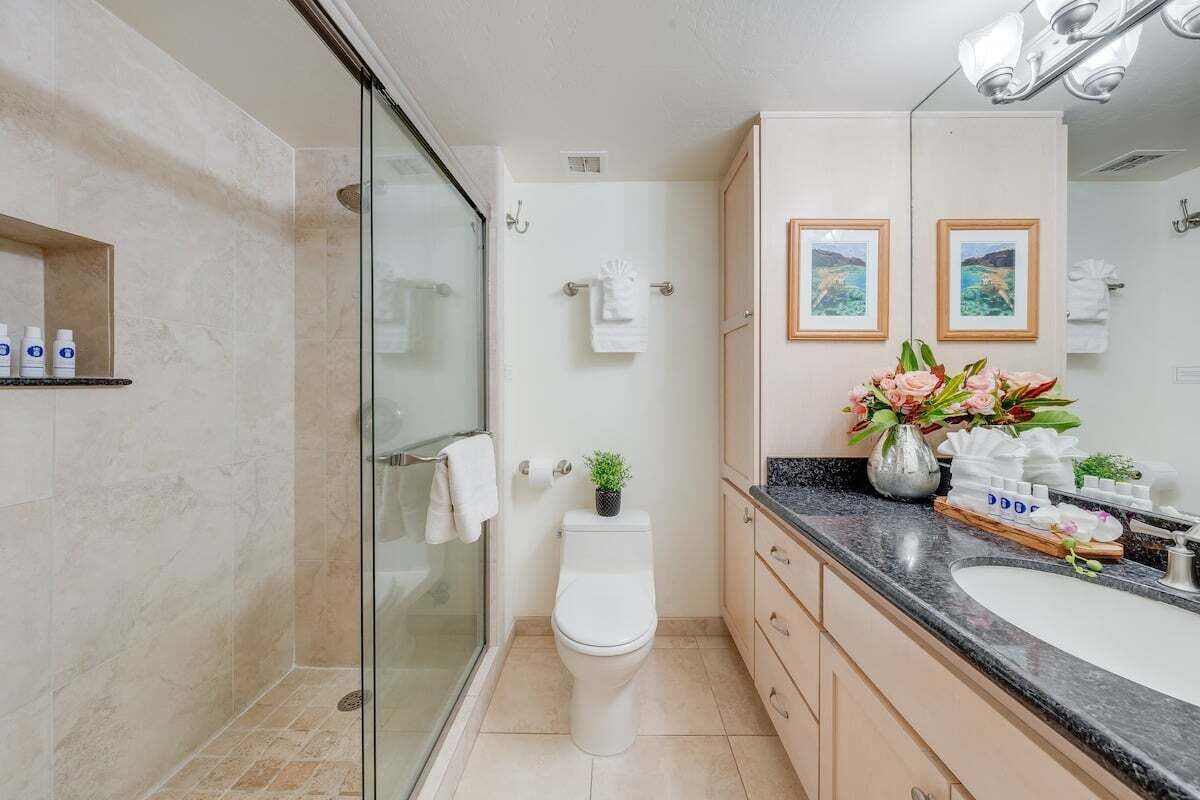 Une salle de bain moderne avec une douche à parois de verre, des toilettes blanches, un meuble-lavabo et un miroir.