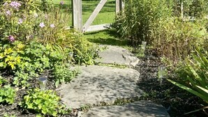 A garden pathway leading to a house with a wooden gate, surrounded by various plants and flowers. - Tower Hill - Hilltop Country Retreat with Panoramic Views  (Millbrook)