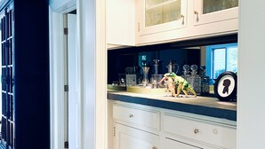 A kitchen with white cabinets, a wooden floor, and a countertop with various kitchen items. - Tower Hill - Hilltop Country Retreat with Panoramic Views  (Millbrook)