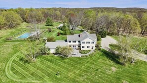 A large, single-story house with a well-maintained lawn and a swimming pool. - Tower Hill - Hilltop Country Retreat with Panoramic Views  (Millbrook)