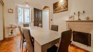 Un coin repas comprenant une grande table, des chaises, une cheminée et un tableau au mur.