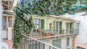 Un immeuble à plusieurs étages doté de balcons, de plantes en pot et d’une vigne à feuilles vertes.