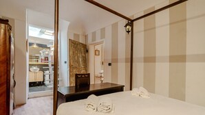 Une chambre dotée d’un lit à baldaquin, d’un bureau en bois, d’un miroir et d’une armoire.