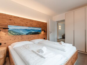 Relax in a serene space with a large bed, a wardrobe, and a beautiful landscape painting above.