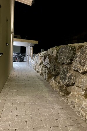Guests can walk along the pathway to the building entrance, flanked by a stone wall and a light-colored wall.