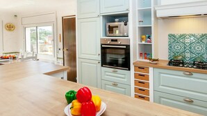 Una cocina moderna con armarios azul claro, encimera de madera y vistas al exterior.