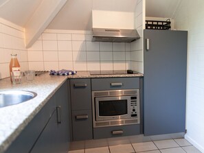 Een koelkast, een vaatwasser, kookgerei, borden en bestek