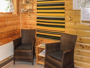Ein Eckzimmer mit zwei Korbstühlen, einem kleinen Tisch und einem gestreiften Wandbehang.