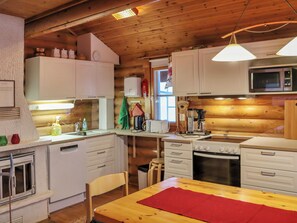 A compact kitchen with wooden cabinets, a microwave, a stove, and a sink.
