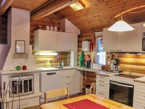 A compact kitchen with wooden cabinets, a built-in oven, and a dining area with a table.