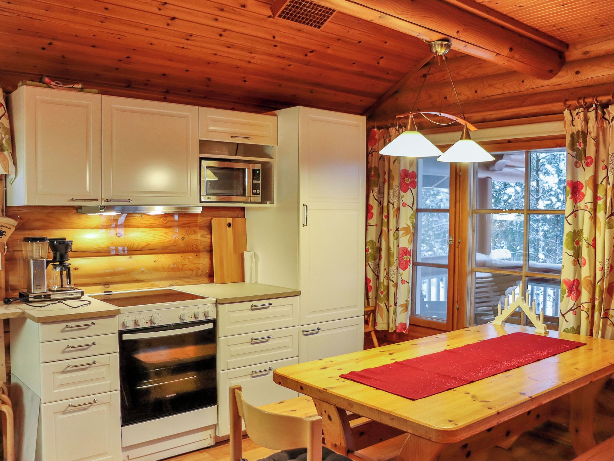 A cozy kitchen with wooden cabinets, a microwave, an oven, and a dining table with a red placemat.
