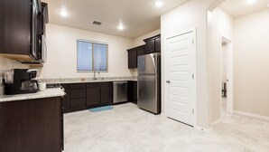 A modern kitchen with dark cabinets, a stainless steel refrigerator, and a built-in oven. - Relaxing Oasis Near White Sands National Monument (Las Cruces)