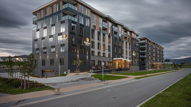 Un hôtel moderne, doté de plusieurs étages, de grandes fenêtres et d’une entrée bien éclairée.