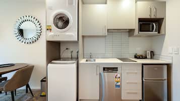 Cocina compacta con lavadora, microondas, refrigerador y comedor con una silla y mesa.
