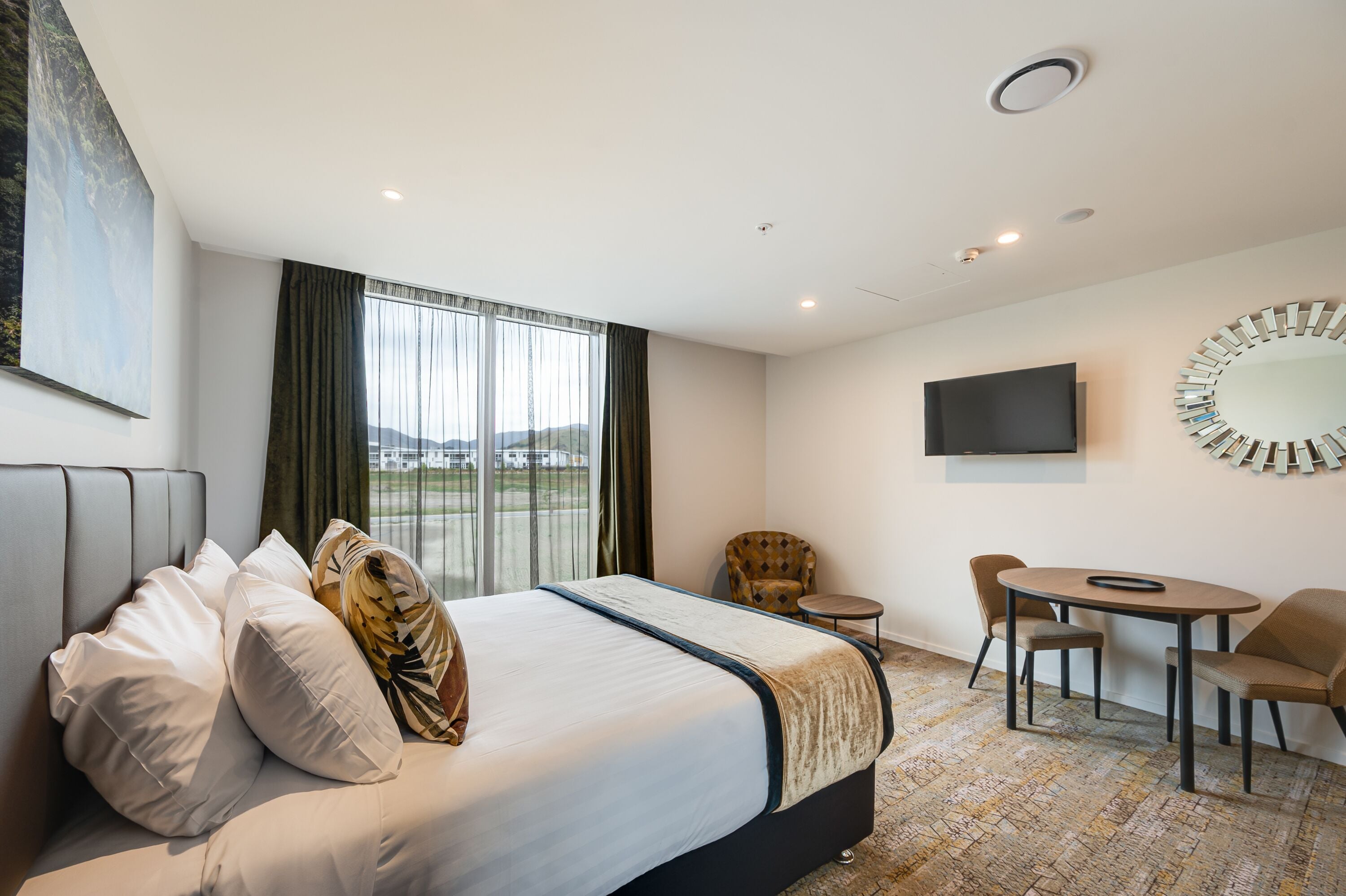 Una habitación de hotel con una cama grande, televisor, escritorio y una silla.