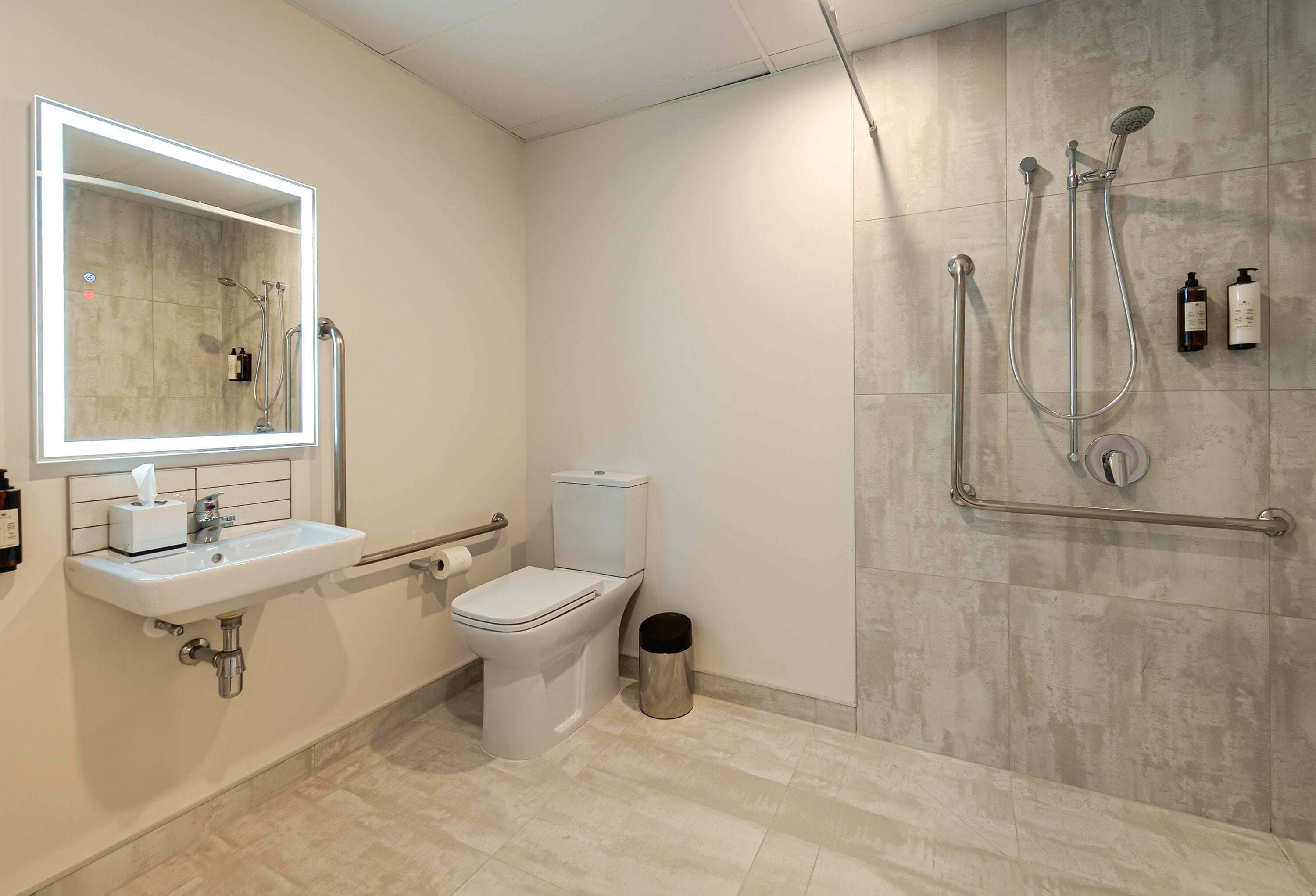 Un baño moderno con inodoro, lavabo, espejo y ducha.