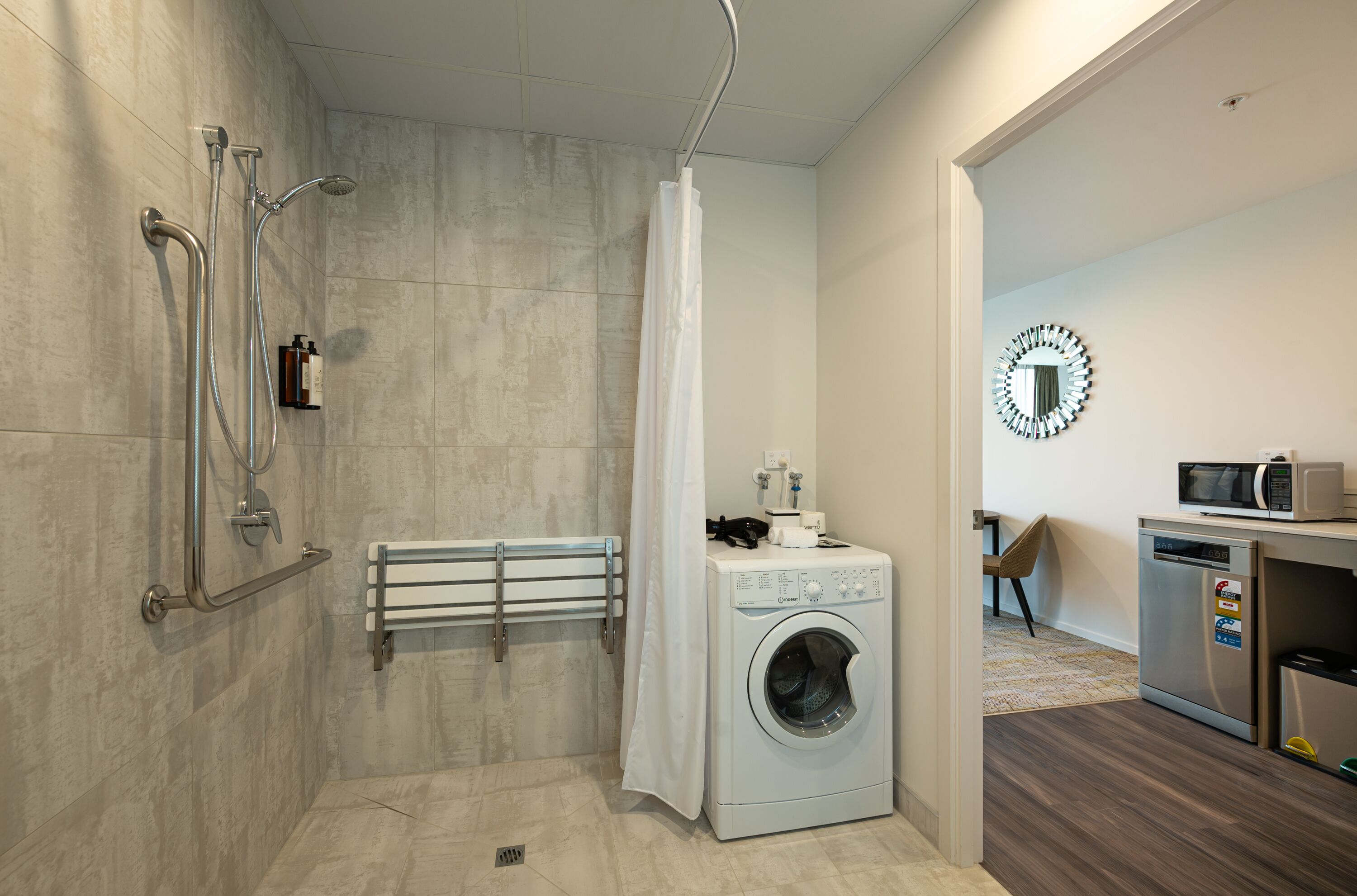 Un baño moderno con ducha, lavadora y microondas.