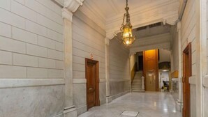 En hall med marmorgolv, trädörrar och en hängande lampa.