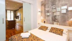 Ett modernt hotellrum med en stor säng, en glasdörr som leder till en matplats och en vägg med en intressant struktur, dekorerad med inramade tavlor.