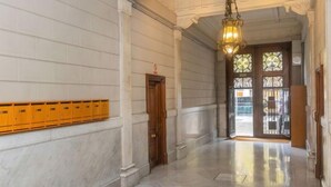 En hall med väggar klädda i marmor, en trädörr och en hängande lampa.