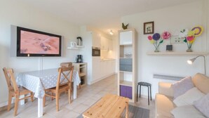 Un salon moderne avec une table en bois, un canapé, un téléviseur et un coin cuisine.