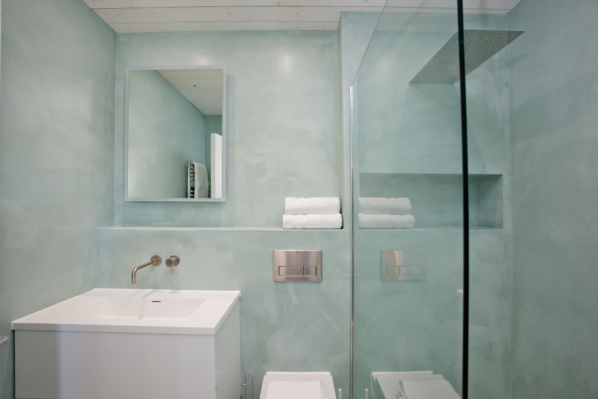 A modern bathroom with a glass shower enclosure, a white sink, and a mirror above it.
