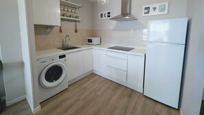 A compact kitchen with a washing machine, microwave, and a refrigerator. - Beach apartment with stunning views (Noja)
