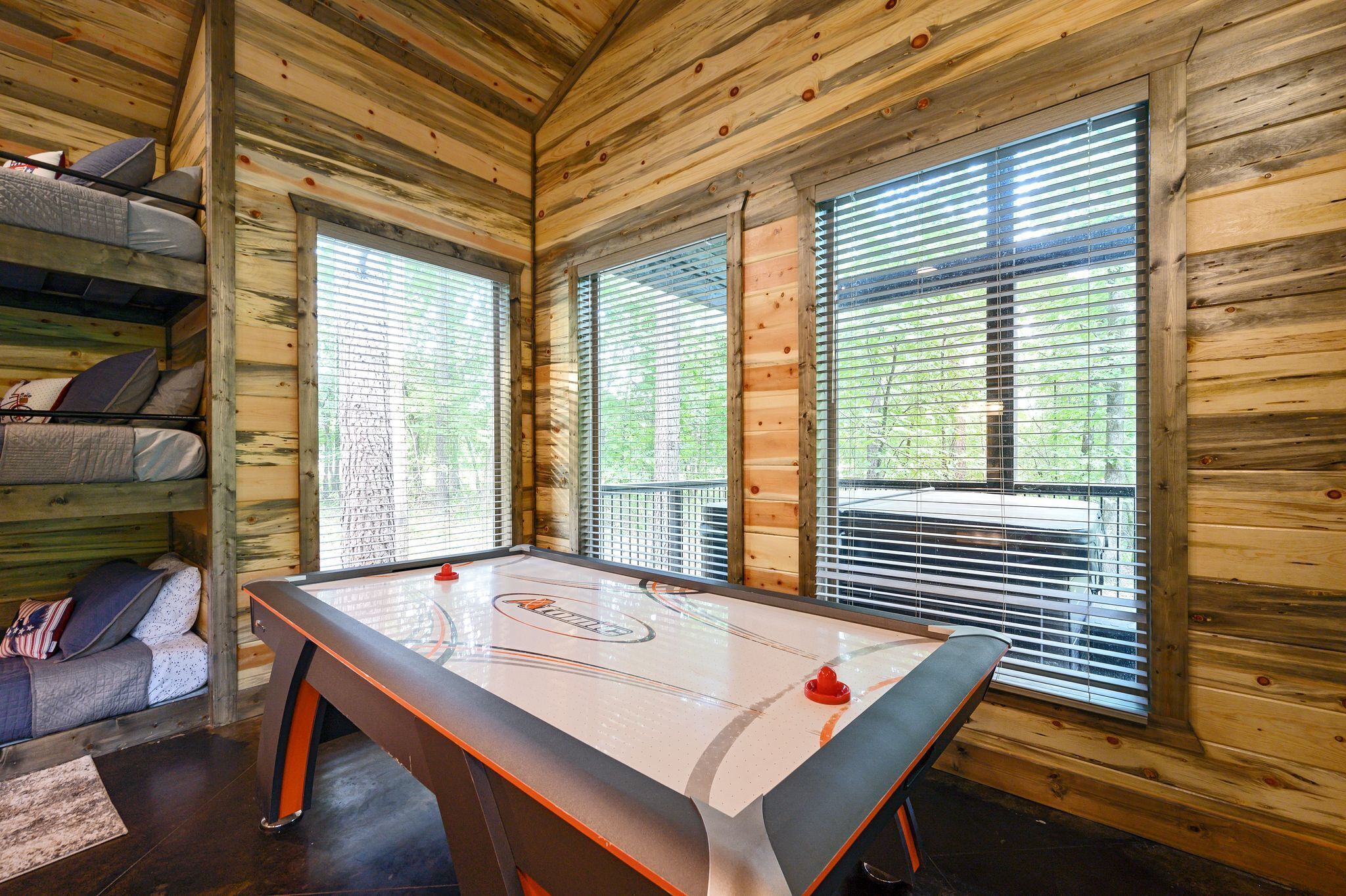 A cozy cabin interior with a pool table, wooden walls, and a bunk bed.