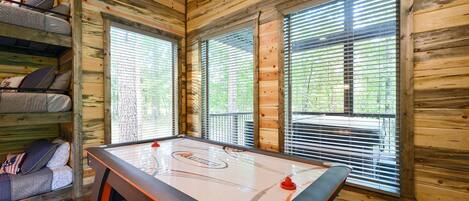 A cozy cabin interior with a pool table, wooden walls, and a bunk bed.