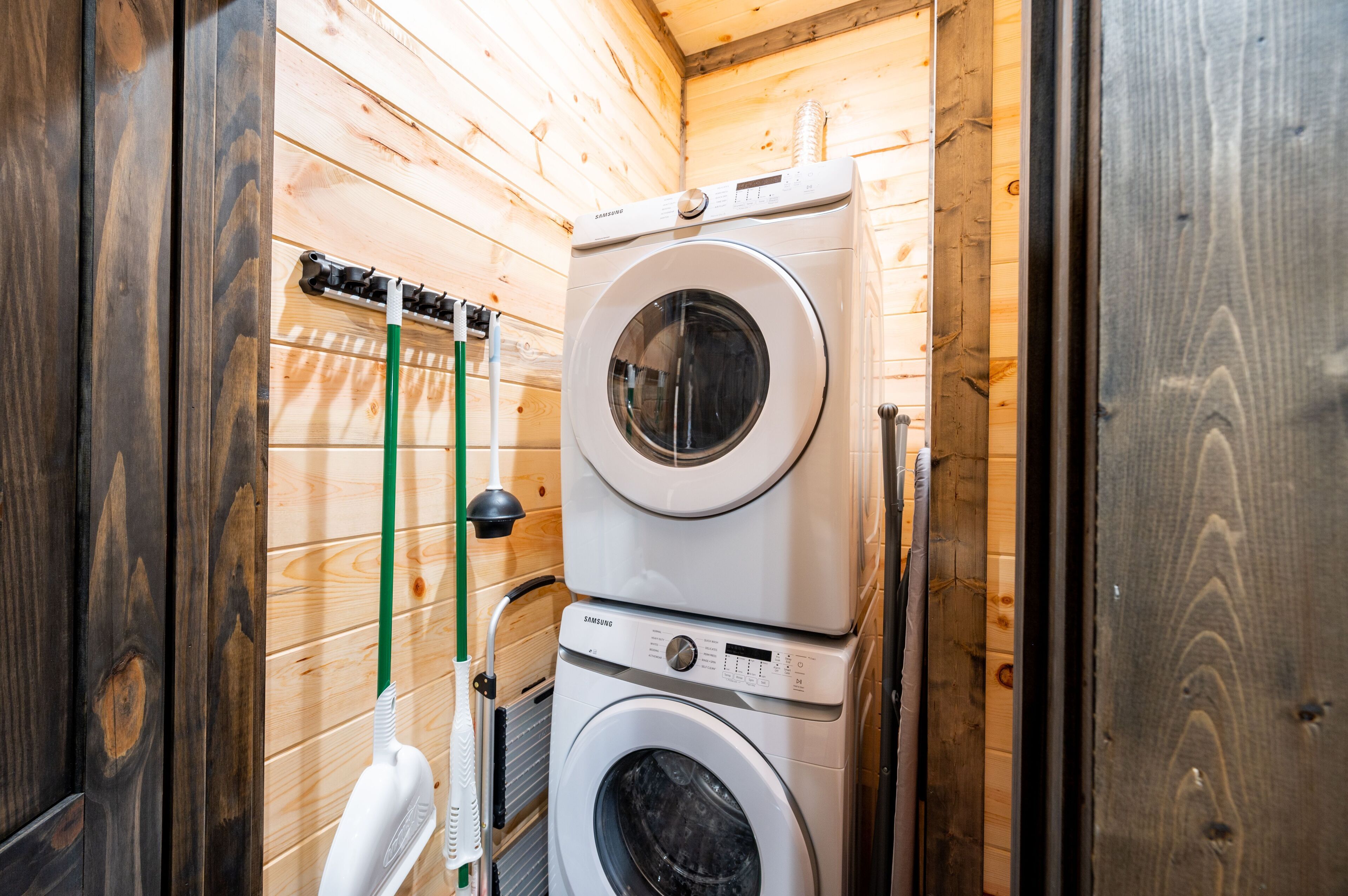 A compact laundry room with wooden walls and a stacked washer and dryer.