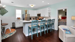 A compact kitchen with white cabinets, a central island with bar stools, a microwave, and a refrigerator.
