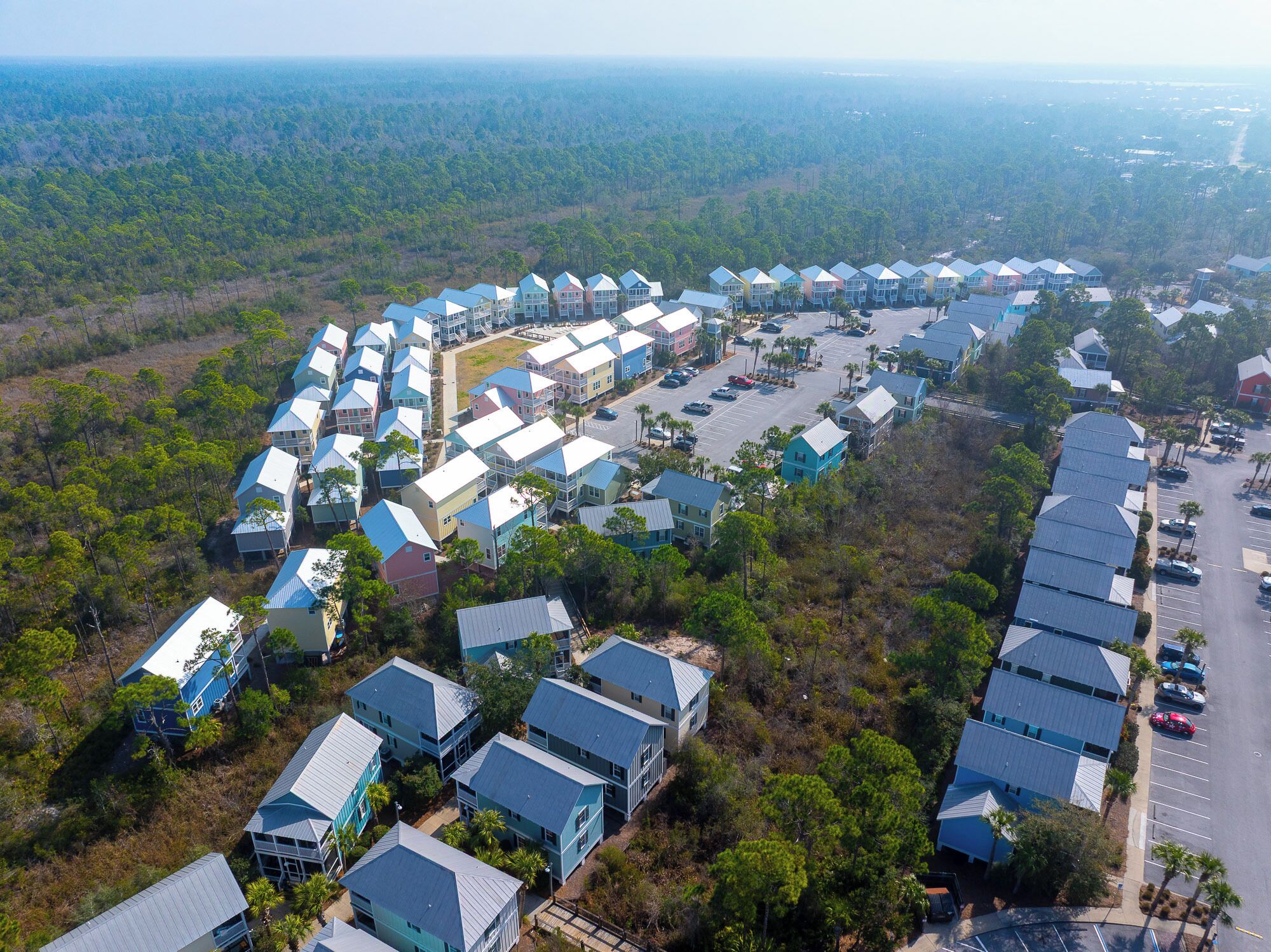 An aerial view of a resort with multiple buildings arranged in a semi-circular layout, surrounded by dense forest.
