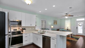 A modern kitchen with white cabinets, stainless steel appliances, and a central island.