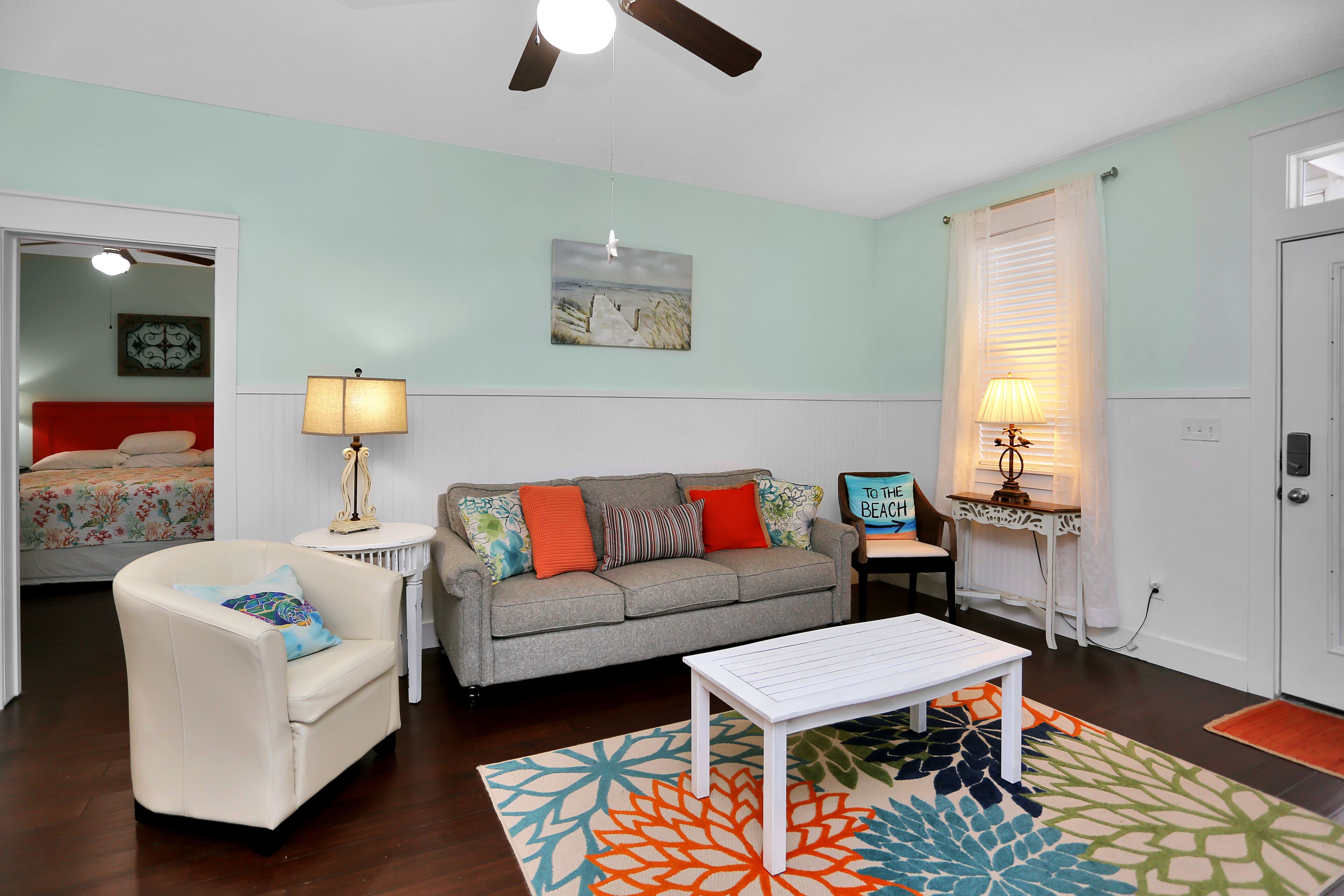 A living room with a sofa, a chair, a coffee table, and a painting on the wall.