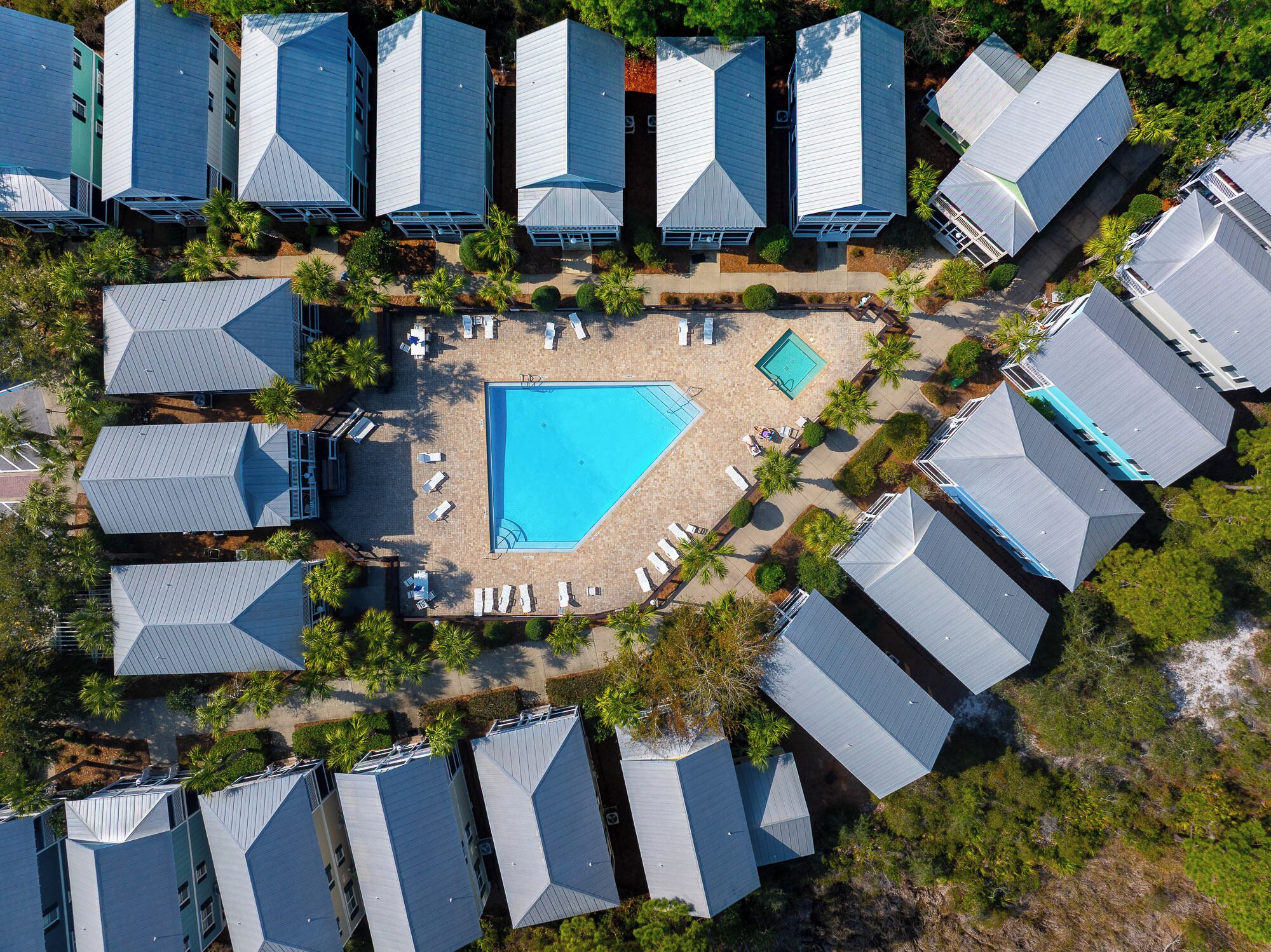 Luchtbeeld van een resort met meerdere gebouwen, een centraal zwembad en omliggende loungegedeeltes.
