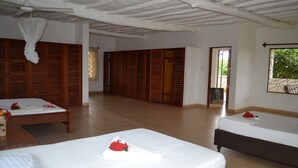A hotel room with two beds, wooden wardrobes, a ceiling fan, and a window with a view of greenery. - Lighthomez Dorric Villas (Diani Beach)