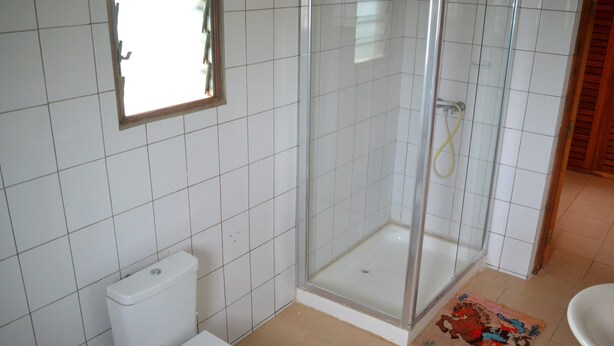A bathroom with a toilet, a glass shower enclosure, and a sink. - Lighthomez Dorric Villas (Diani Beach)