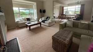 A spacious living room with two sofas, a coffee table, and a wicker ottoman.