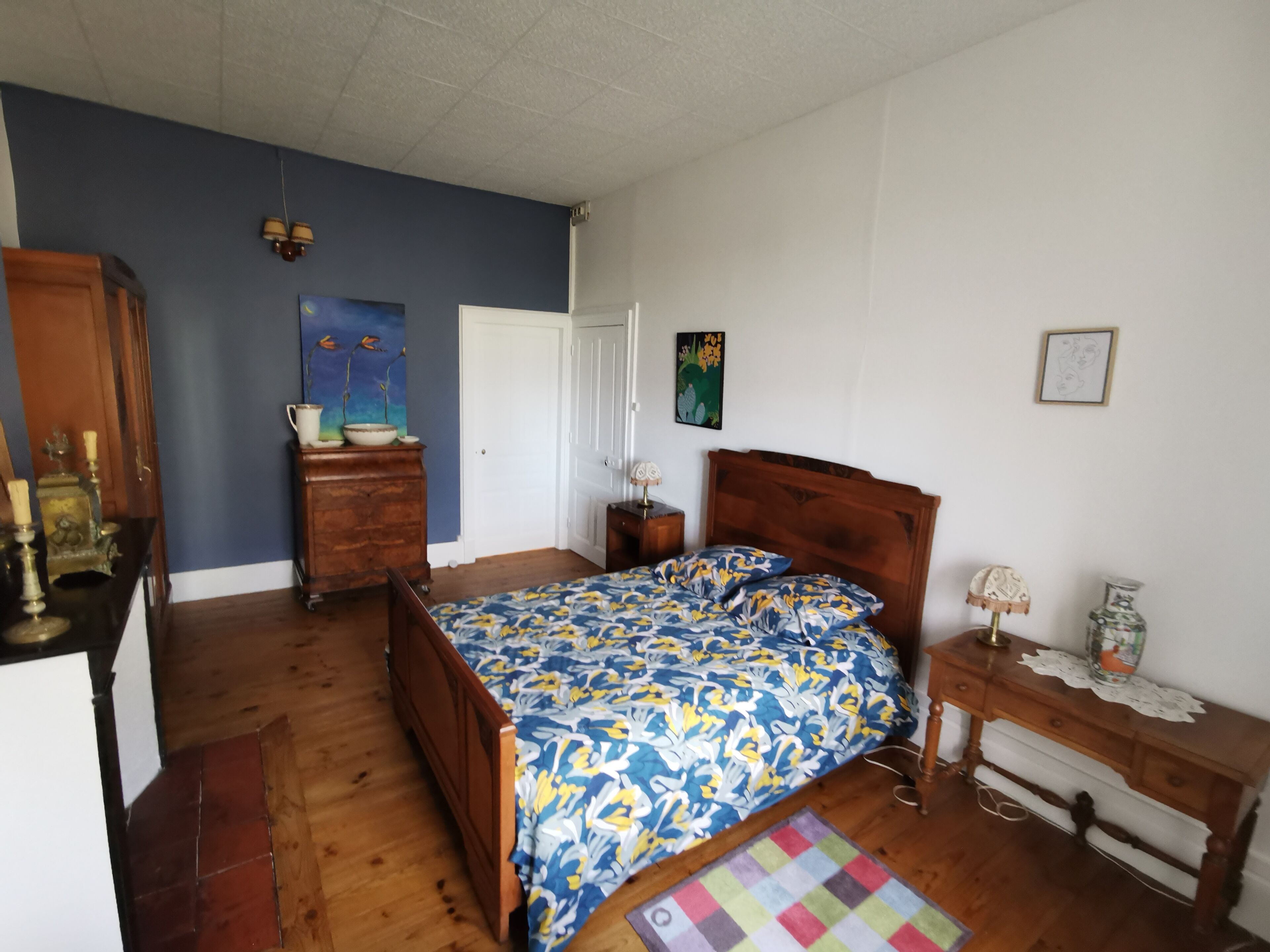 Un dormitorio con una cama de madera, un aparador, una mesita de noche y un cuadro en la pared.