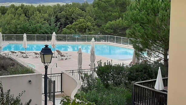 Une piscine entourée de chaises longues et de parasols, avec une végétation luxuriante et des montagnes en toile de fond.