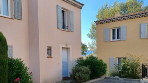 Un quartier résidentiel comprenant deux maisons, l’une de couleur pêche et l’autre jaune, toutes deux dotées de volets et d’un petit jardin.