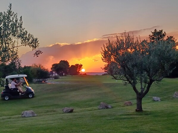 A golf course with a golf cart, trees, and a sunset in the background. - Villa 4/6p Avec 2 Chambres (Mallemort)
