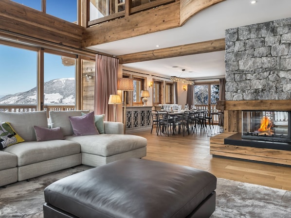 A spacious living room with a fireplace, a dining area, and a sofa with cushions.