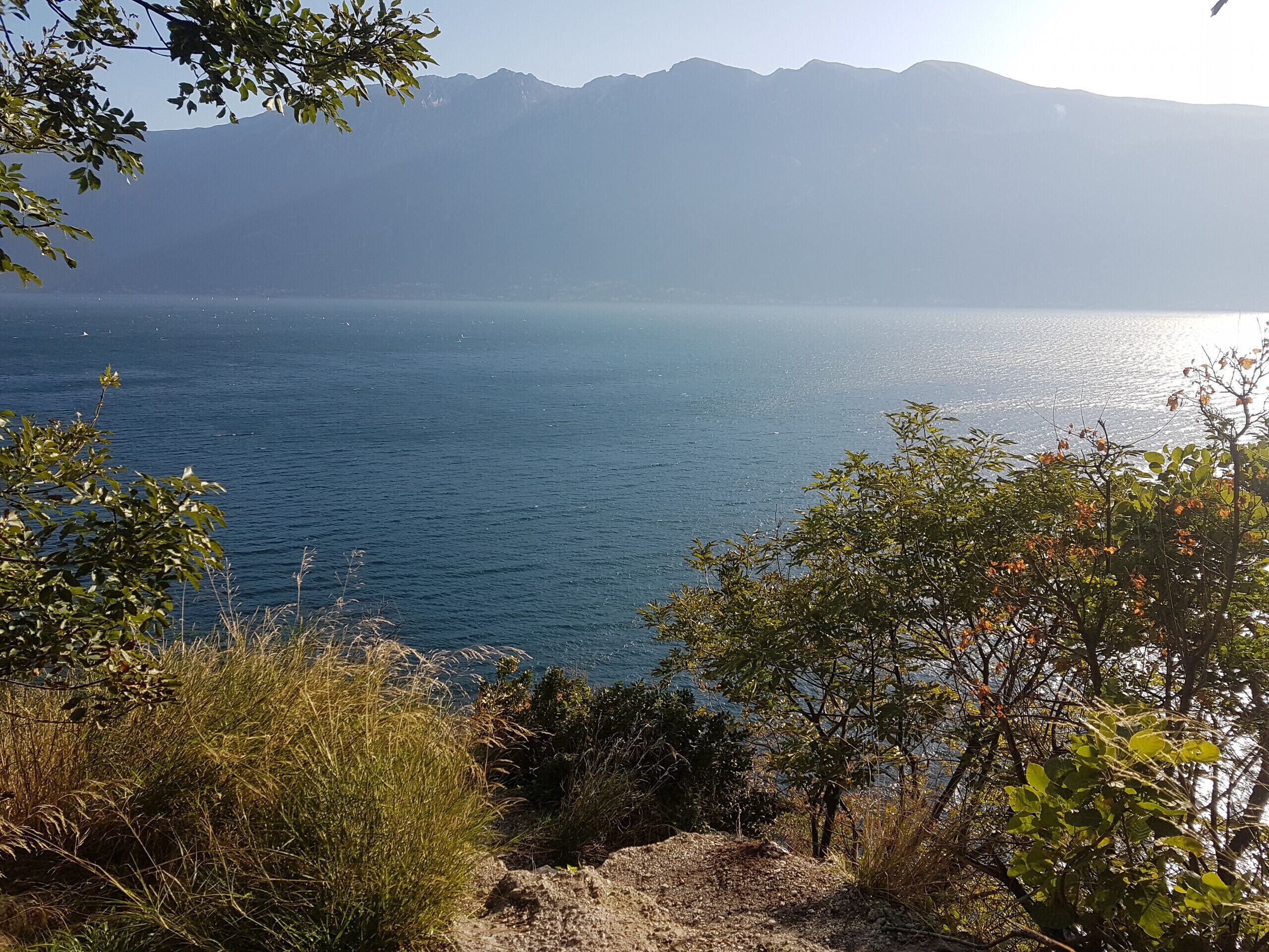 A coastal landscape with a clear view of the sea and distant mountains.