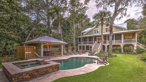 Ein zweistöckiges Haus mit Swimmingpool, überdachter Terrasse und einer Holzterrasse.