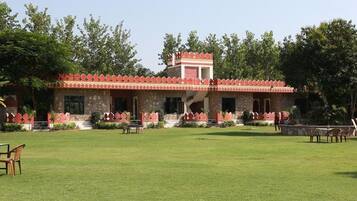 Traditional building with a central tower and arched facade, set amidst a serene lawn and trees.