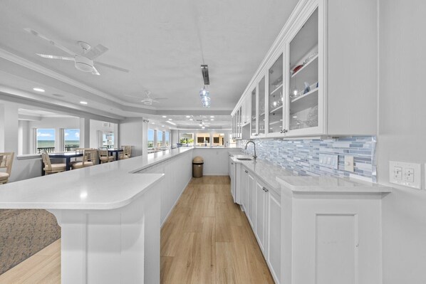 Une cuisine moderne avec des meubles blancs, un grand îlot central et une vue sur la salle à manger.