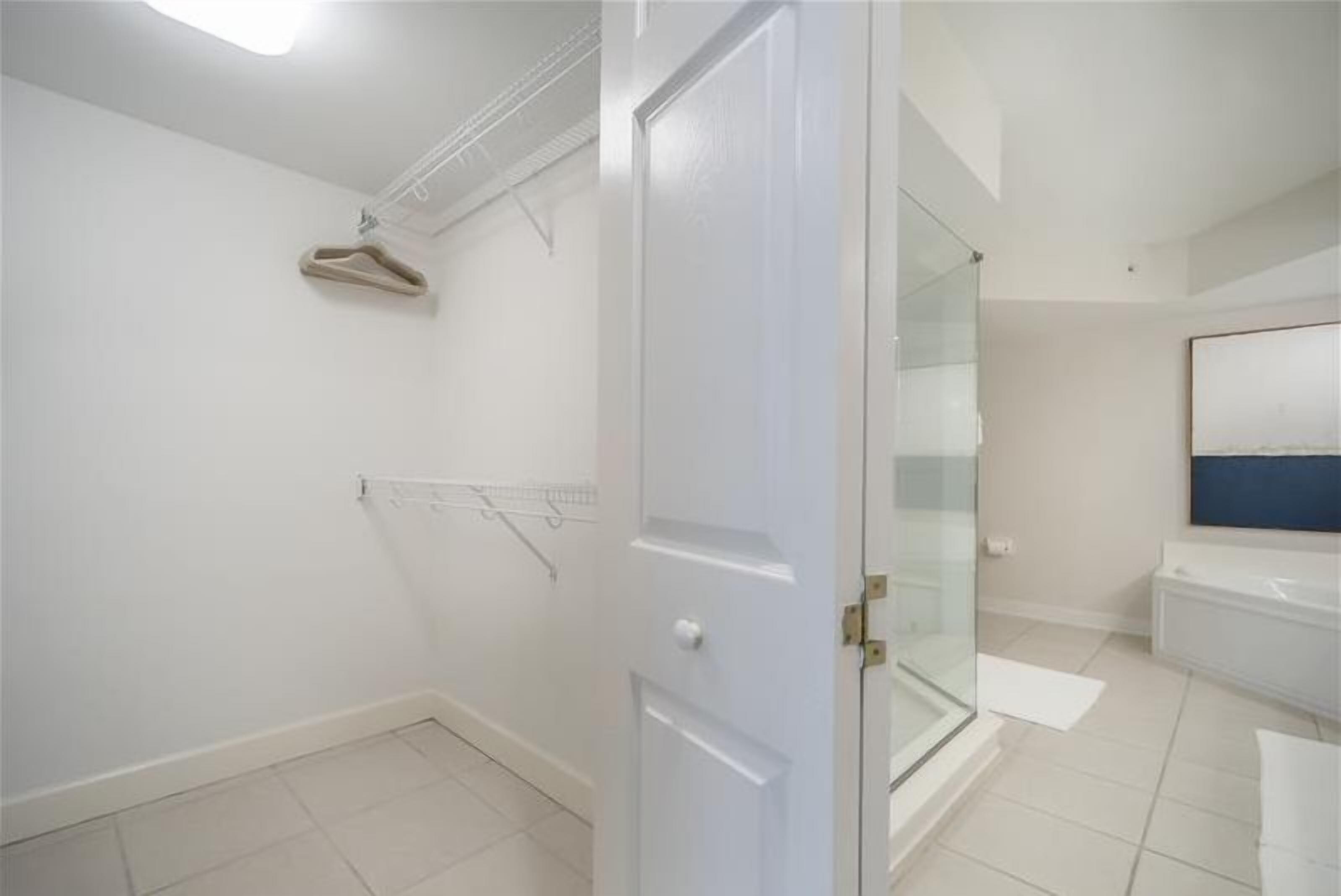 Casa de banho com chuveiro em cabine de vidro, lavatório branco e um porta-toalhas.