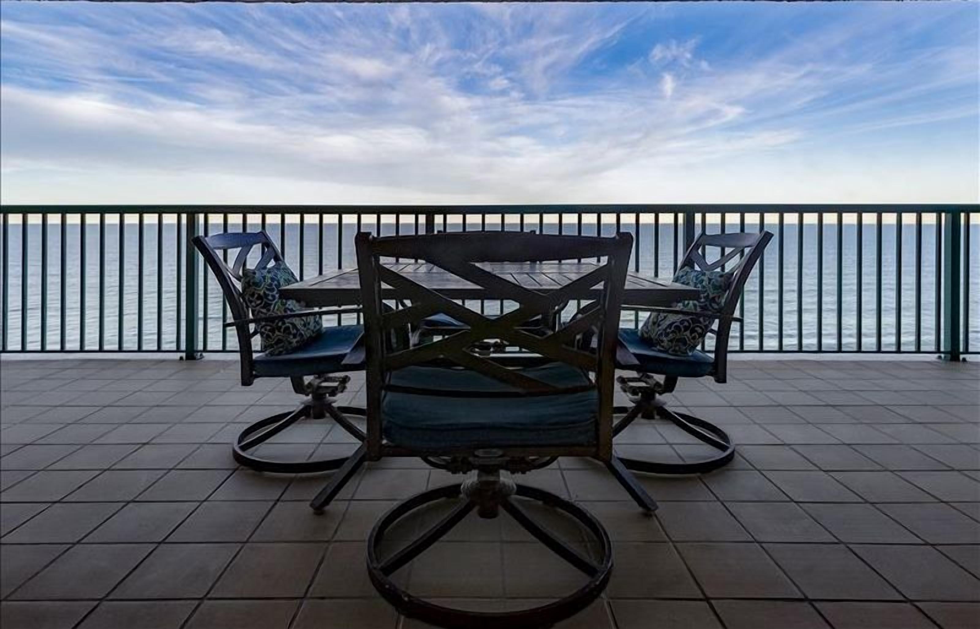 Una terraza con dos mecedoras y una mesa, con vistas a un cuerpo de agua.