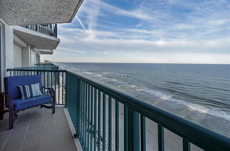 A balcony with a blue sofa and a view of the ocean.